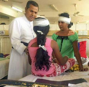 Fr Basil visiting a mother and child in hospital - victims of the terror attacks